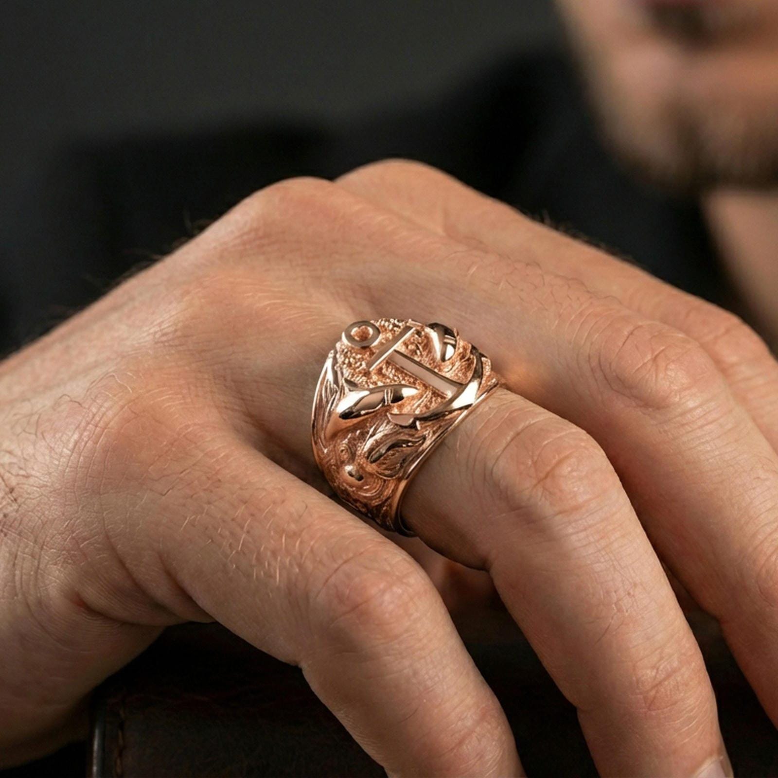 Rose gold plated anchor and shark ring worn on a finger, close-up lifestyle photo focusing on the raised anchor centerpiece
