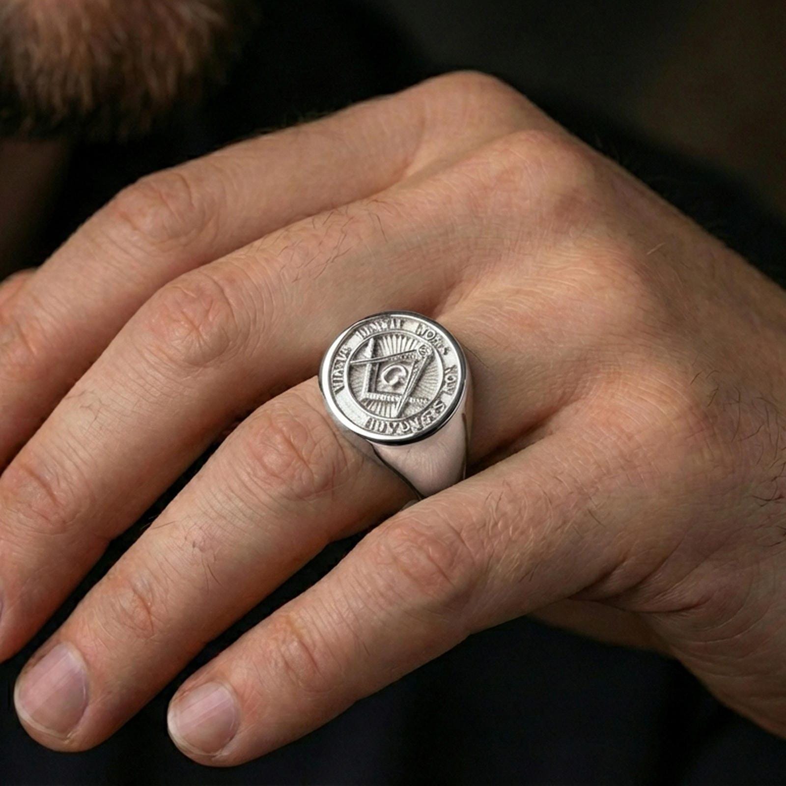 Polished silver Freemason signet ring on the finger, wearable shot emphasizing crisp engraving and clean metallic shine