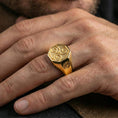 Load image into Gallery viewer, Gold plated Celtic triskelion octagon signet ring worn on a finger, lifestyle image focusing on the bold swirl engraving and side emblem
