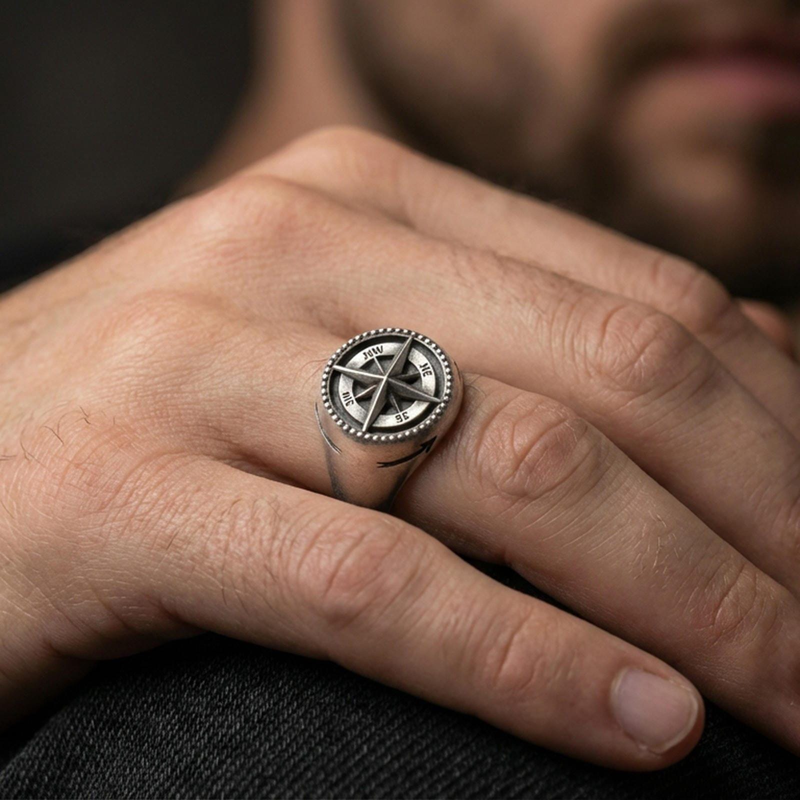 Oxidized compass signet ring worn on a finger, close-up lifestyle photo highlighting the raised wind rose star and beaded rim