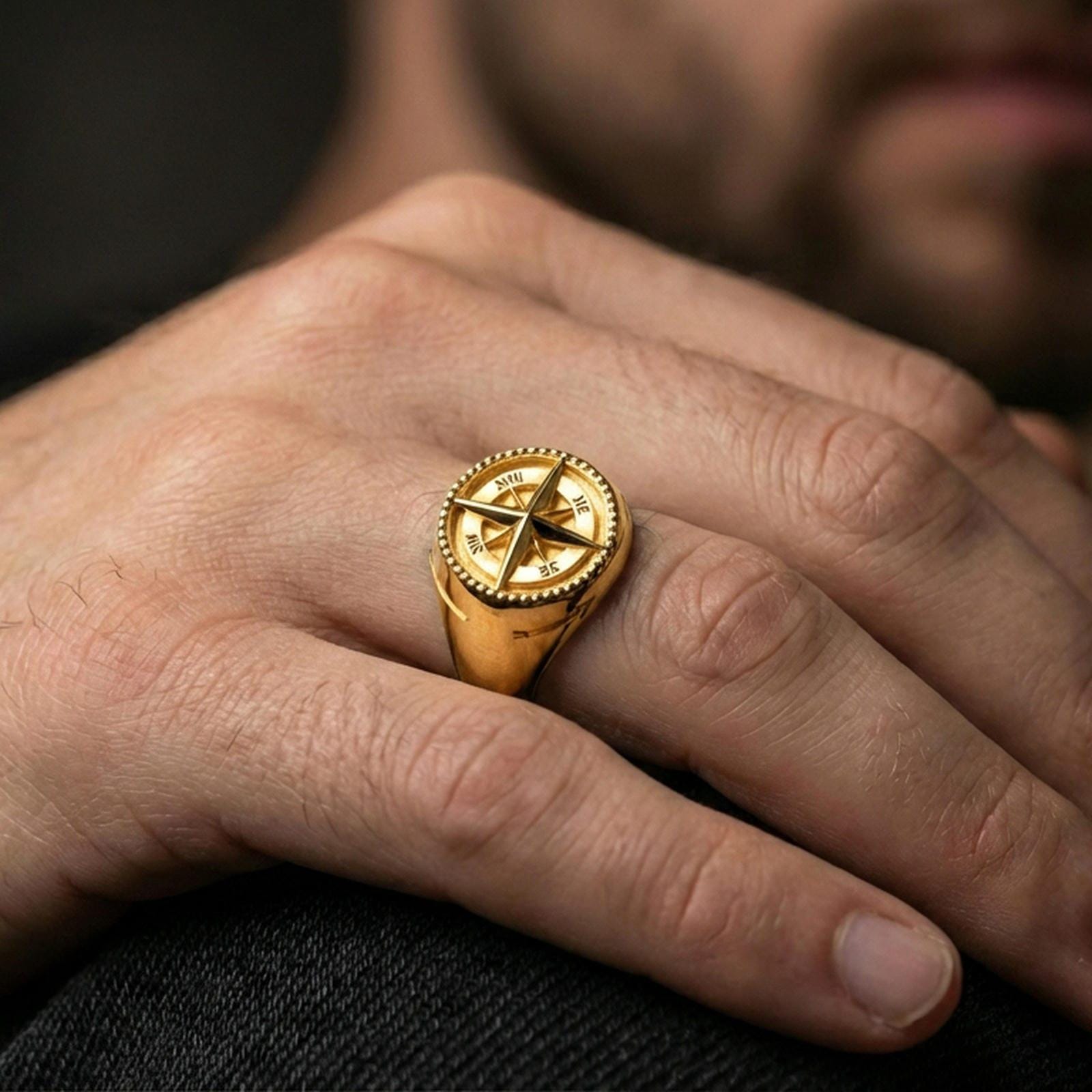 Gold plated compass signet ring worn on a finger, lifestyle image emphasizing the directional letters and star relief details