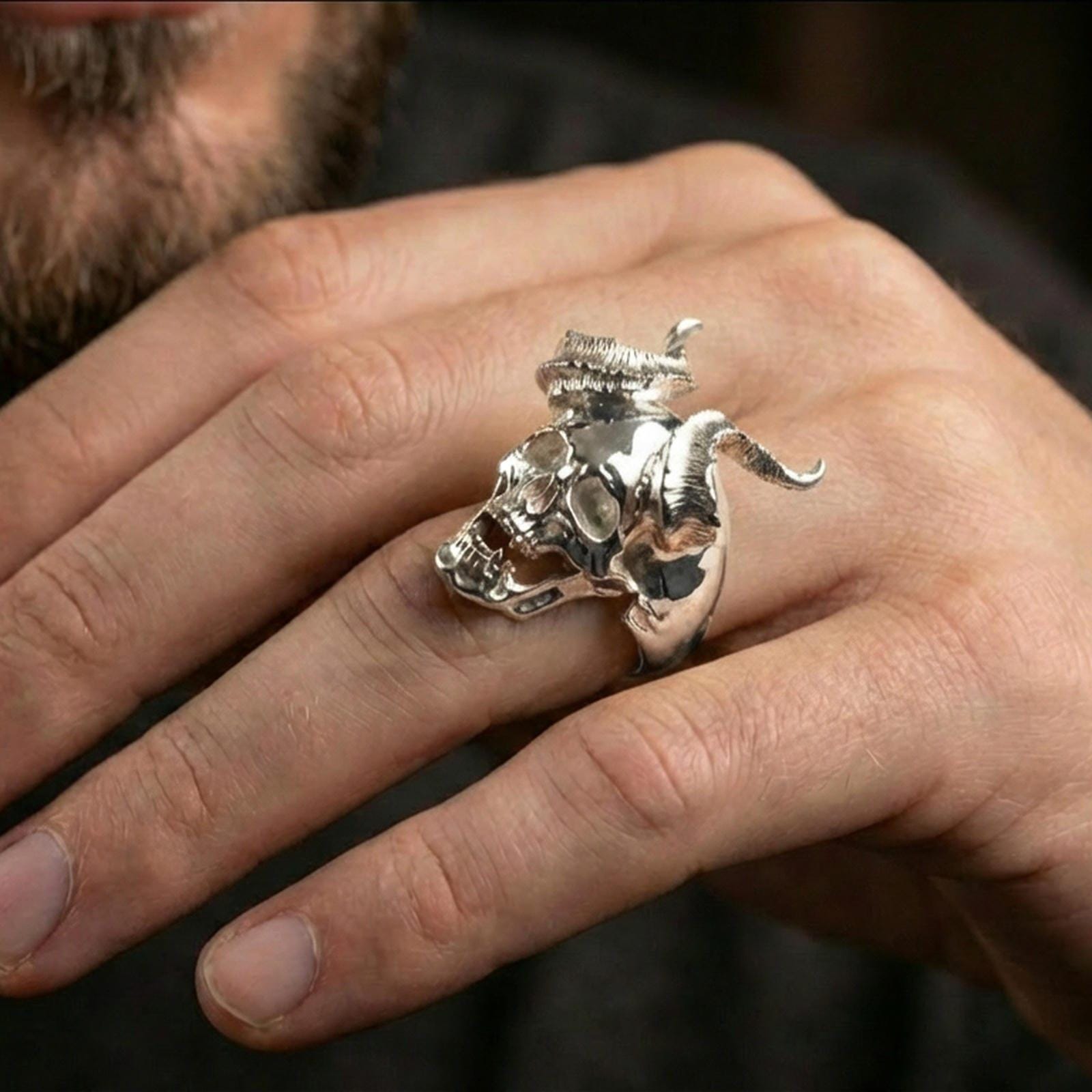 Polished silver horned skull ring on the finger, wearable shot focusing on the sculpted teeth and horn texture