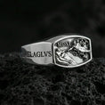 Load image into Gallery viewer, Polished silver Saint Michael ring showing carved “MICHAEL” text and high-relief heavenly battle scene, close-up on volcanic stone

