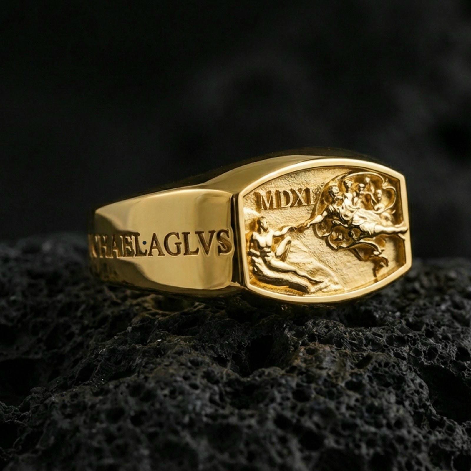 Gold plated Archangel Michael signet ring with Roman numeral MDXI and detailed relief artwork, product-only macro shot on black volcanic rock