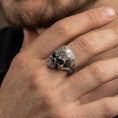 Load image into Gallery viewer, Oxidized baroque skull ring worn on a finger, lifestyle close-up emphasizing the engraved scroll texture and darkened recesses
