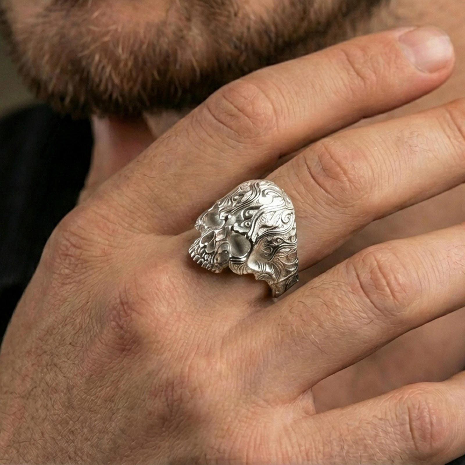 Polished silver skull signet ring on the finger, wearable photo focusing on the ornate filigree carving and bold gothic silhouette