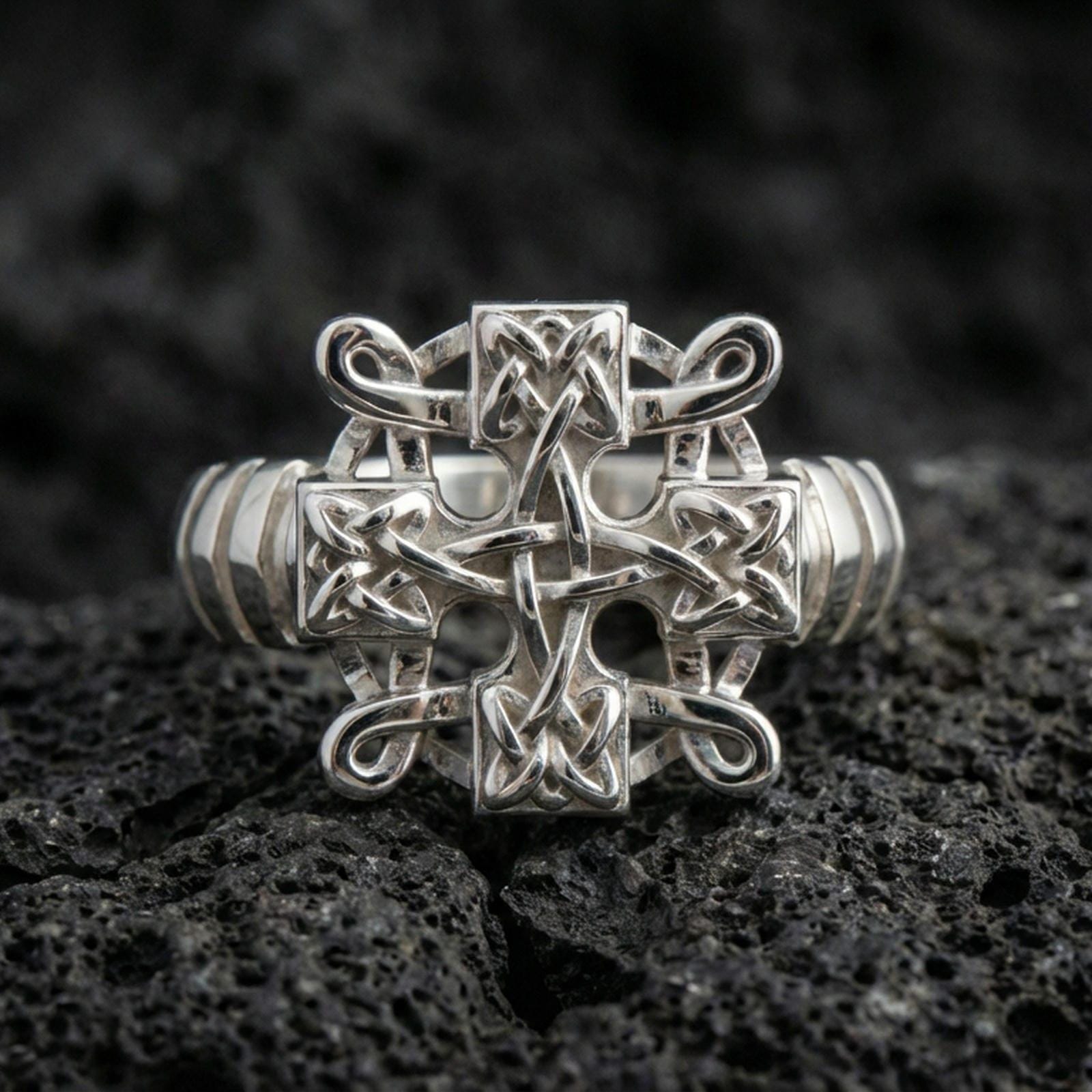 Polished silver Celtic knot cross ring featuring crisp interwoven knotwork and smooth edges, close-up product shot on volcanic stone