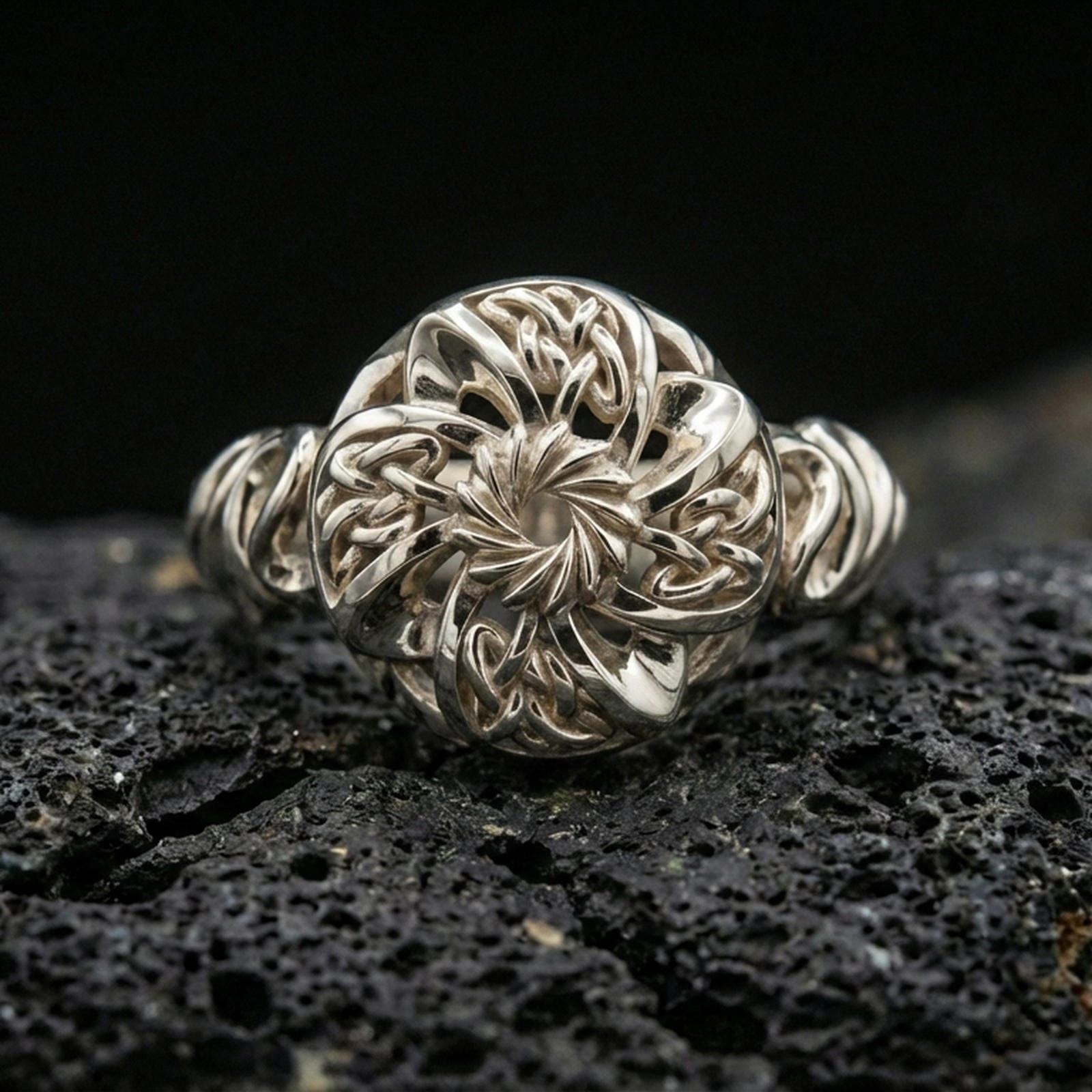 Polished silver Celtic windflower ring featuring a sculpted flower swirl center and Celtic knotwork petals, close-up on volcanic stone