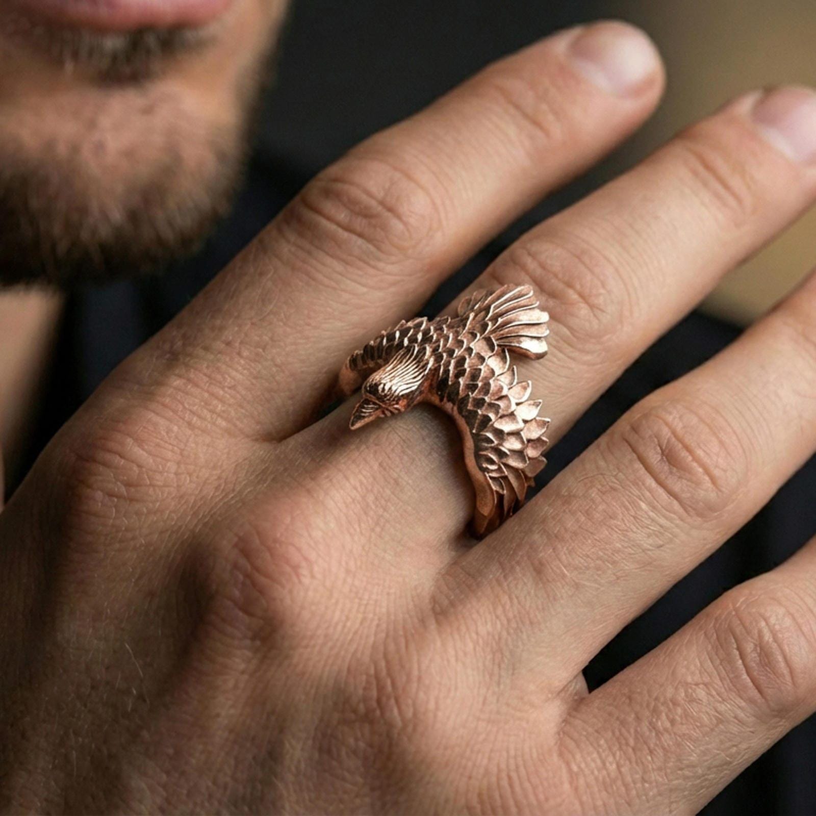 Rose gold plated wing open band ring on the finger, lifestyle shot showcasing the feathered wing silhouette and sculpted head detail