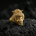 Load image into Gallery viewer, Gold plated geisha skull ring with engraved hair strands, floral crown details, and skull face design, product-only macro image on black volcanic rock
