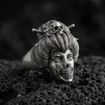 Load image into Gallery viewer, Oxidized sterling silver geisha skull ring with detailed hair bun, floral ornaments, and skeletal jaw, macro product photo on black volcanic rock
