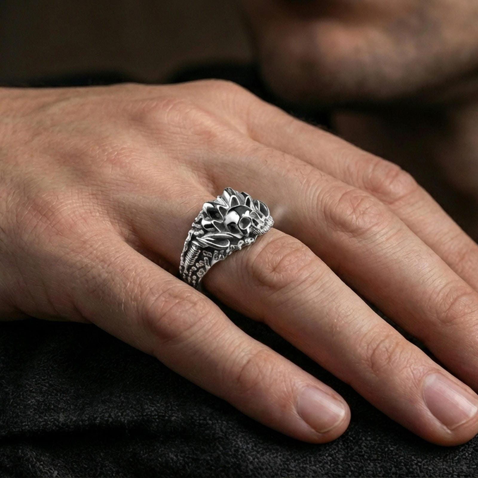 Polished silver skull ring on the finger, wearable photo emphasizing the raised crest and industrial chain texture