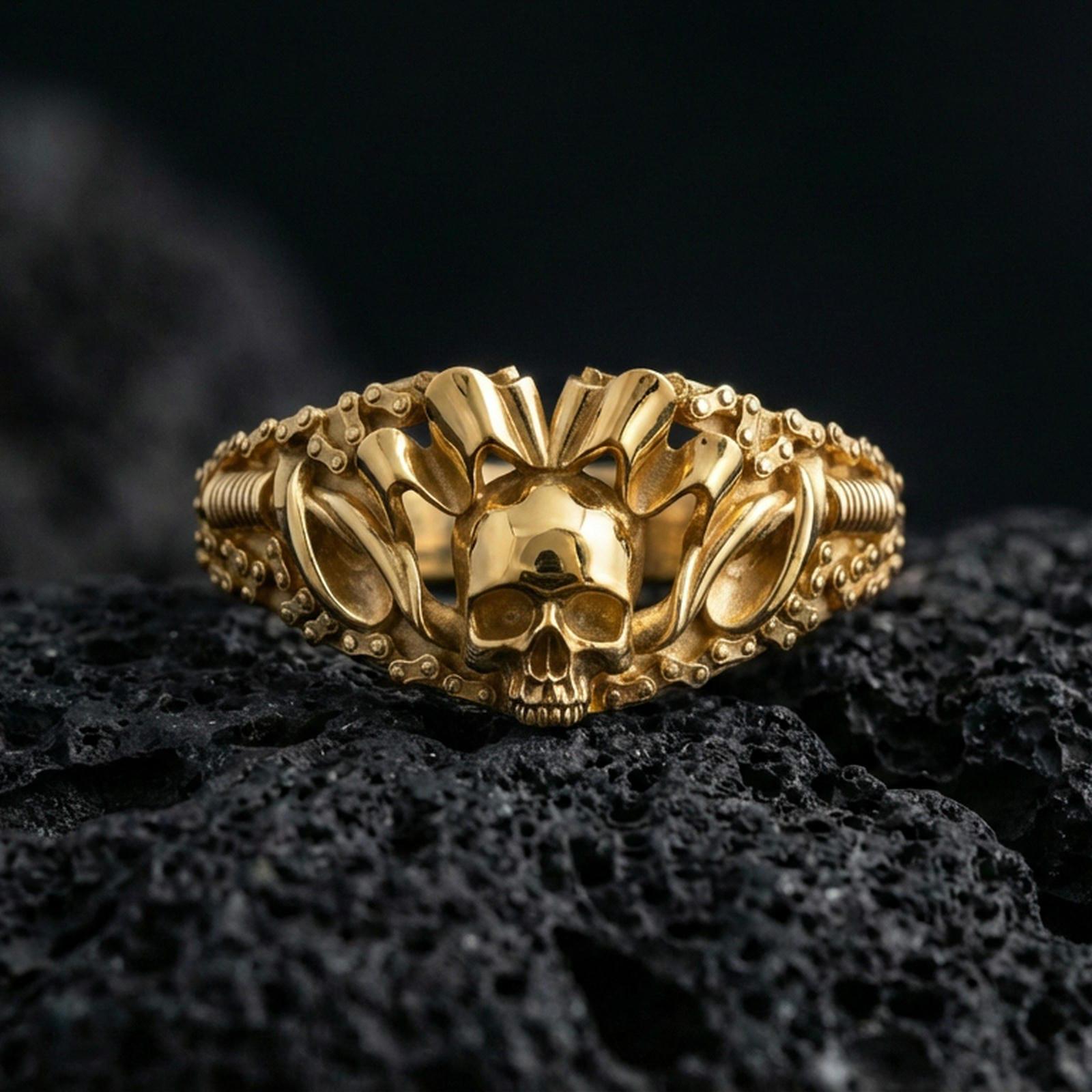 Gold plated skull ring with sculpted skull face, bold crown spikes, and chain-style band pattern, product-only macro image on volcanic rock