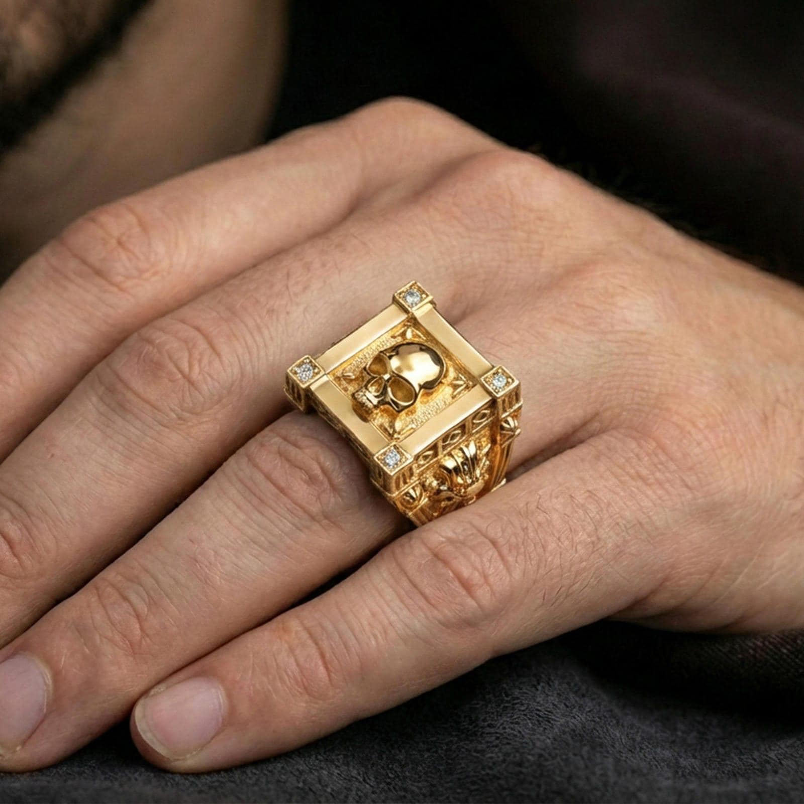 Gold plated skull ring worn on a finger, close-up lifestyle image highlighting the framed skull face and lab diamond accents