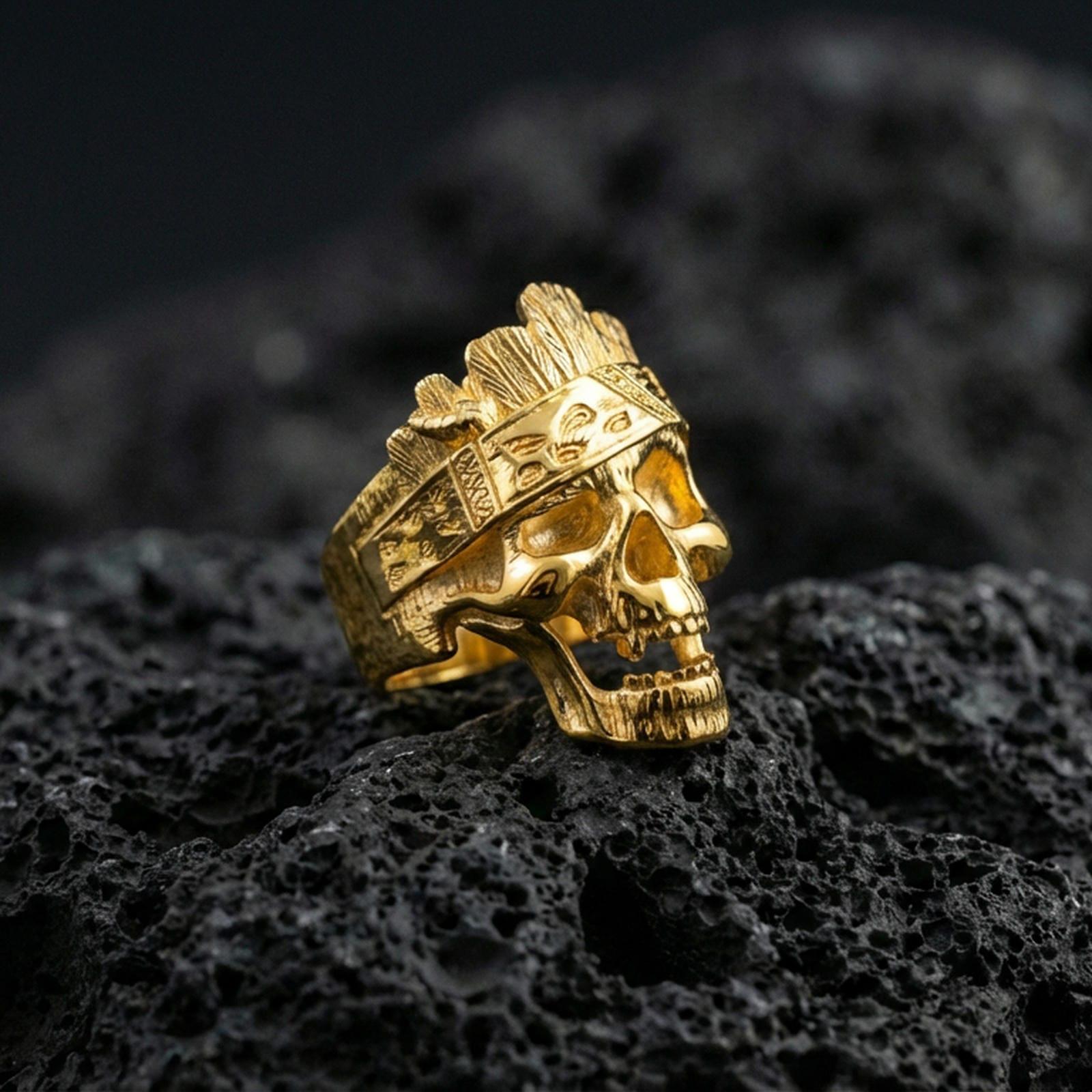 Gold plated woodgrain skull ring with carved bark texture and engraved band accents, product-only macro image on volcanic rock