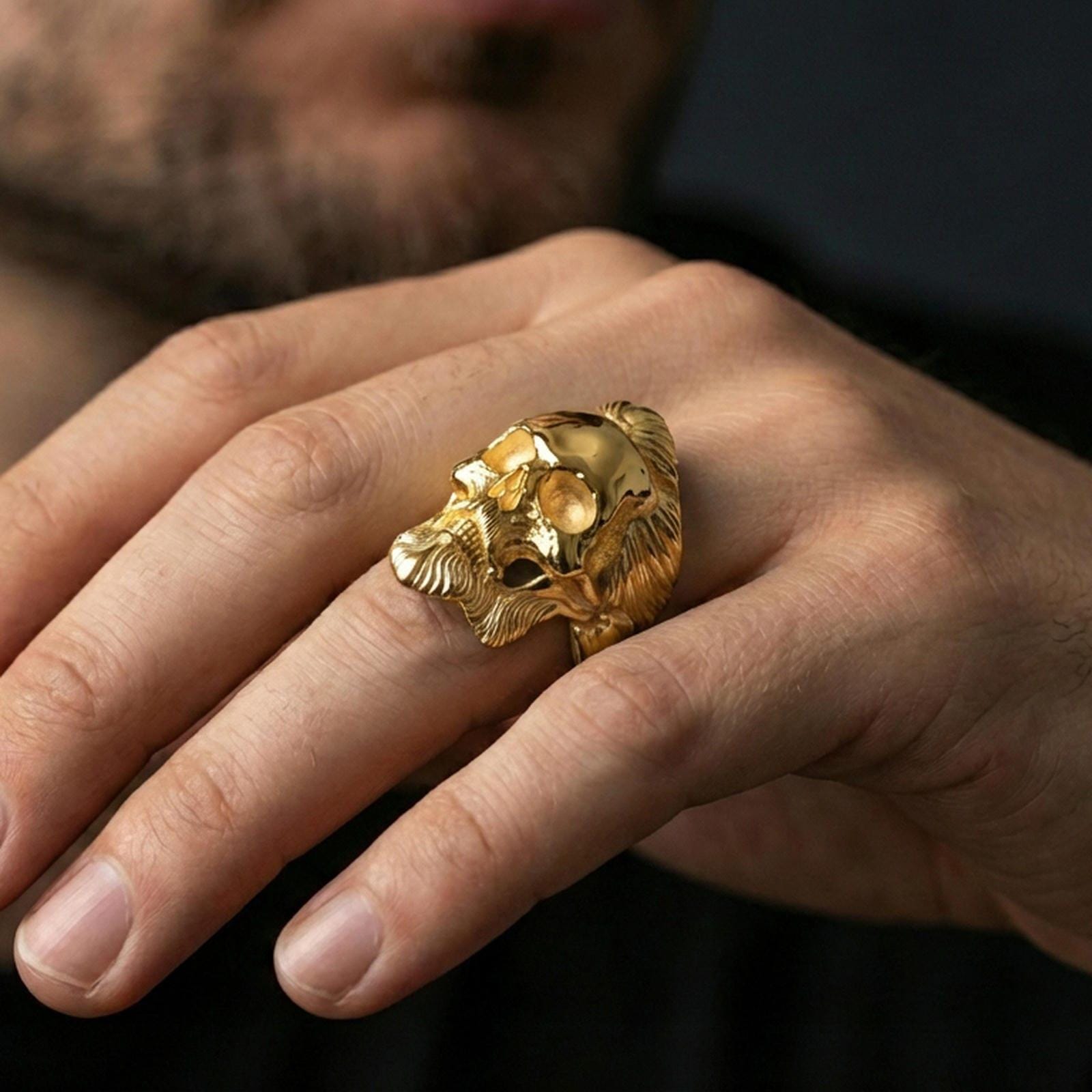 Gold plated bearded skull ring worn on a finger, close-up lifestyle image showcasing the carved hair and beard relief