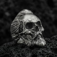 Load image into Gallery viewer, Oxidized sterling silver skull ring with sculpted beard and swept-back hair, macro product photo on black volcanic rock
