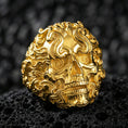 Load image into Gallery viewer, Gold plated smoke skull ring with sculpted swirling curls and textured skull relief, product-only macro on black volcanic rock
