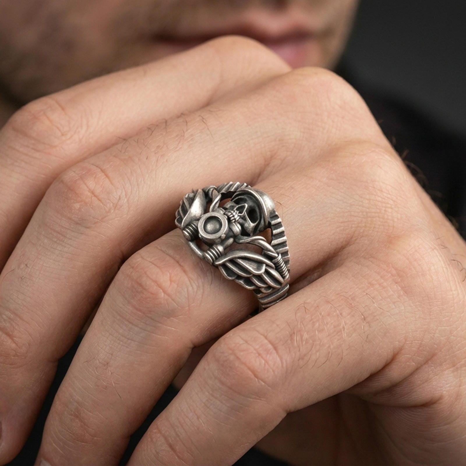 Oxidized biker skull ring worn on a finger, close-up lifestyle shot highlighting winged details and motorcycle-inspired design