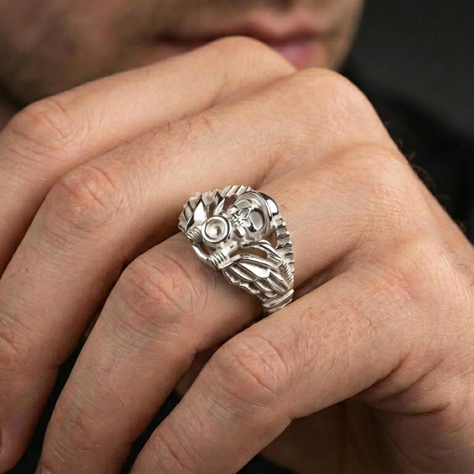 Polished silver motorcycle skull ring on the finger, wearable close-up focusing on the skull centerpiece and mechanical styling