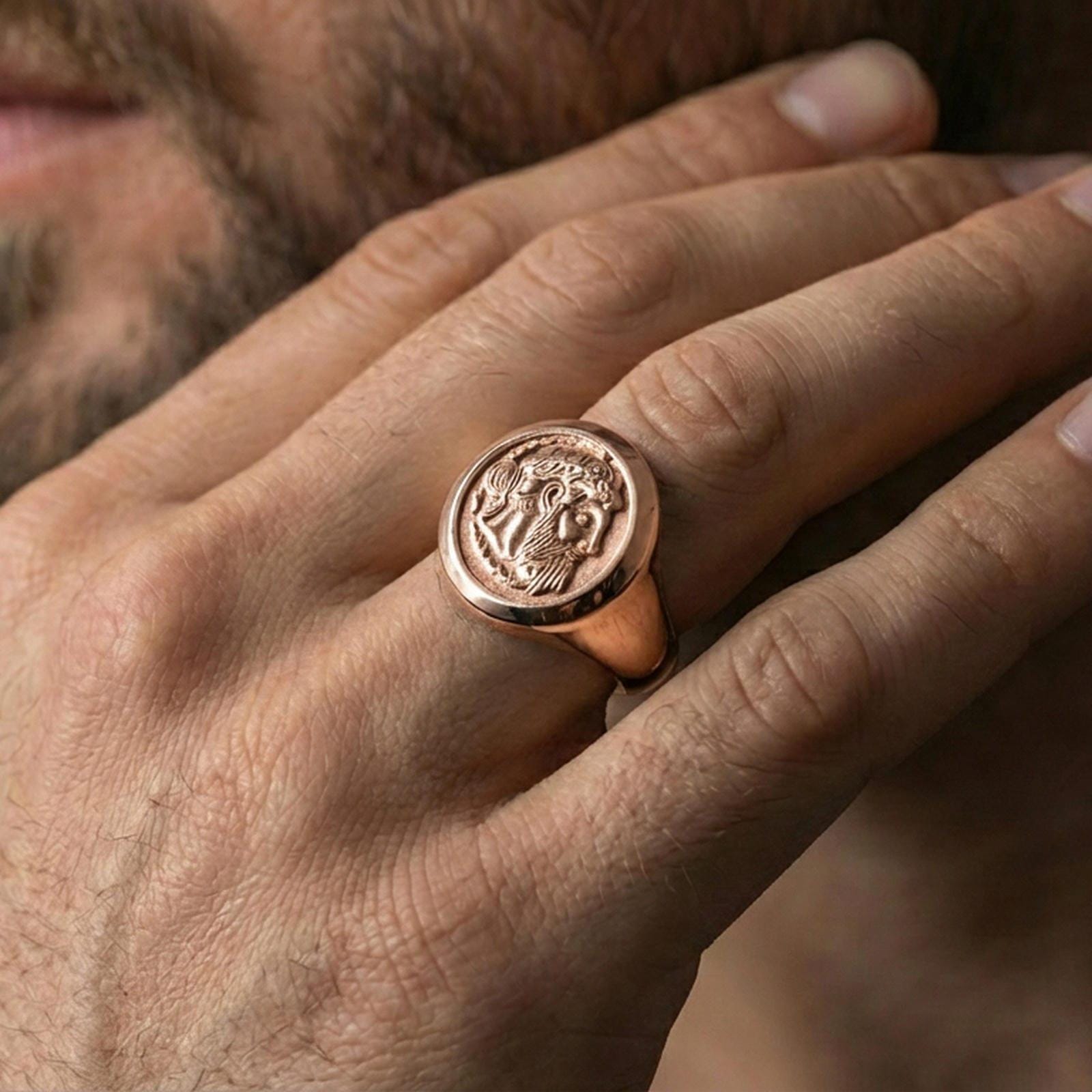 Rose gold plated ancient coin signet ring on the finger, close-up lifestyle image showing the portrait relief and metal texture