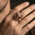 Load image into Gallery viewer, Rose gold plated horned skull ring on the finger, close-up lifestyle image showing the horned skull design and metal texture
