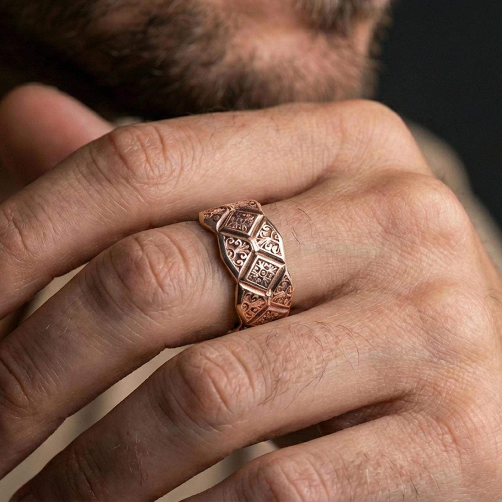 Rose gold plated ornate engraved band ring worn on finger, detailed diamond panels and filigree engraving, elegant lifestyle wear shot.