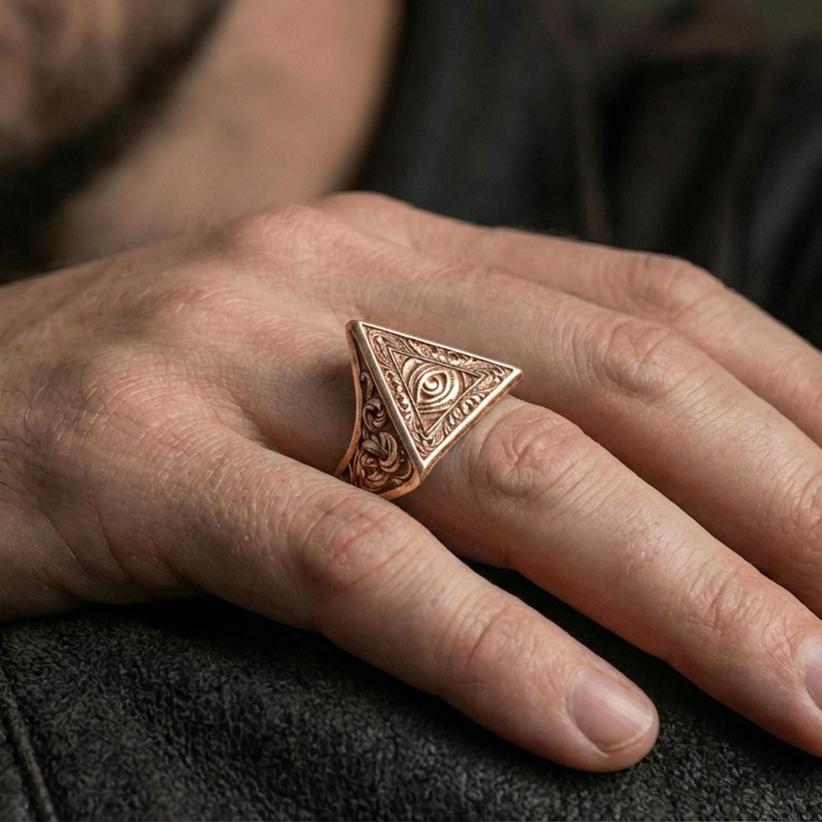 Rose gold plated all-seeing eye triangle ring on the finger, close-up lifestyle image focusing on the engraved filigree and pyramid face
