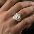 Load image into Gallery viewer, Polished silver sigil signet ring on the finger, wearable close-up emphasizing the oval face and crisp carved symbol
