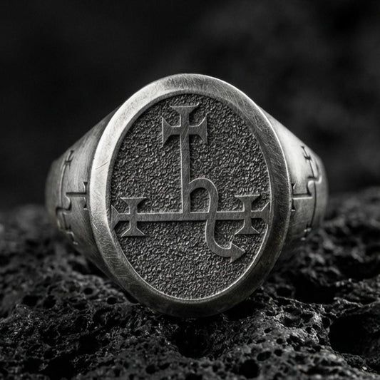 Oxidized sterling silver oval signet ring with engraved demonic sigil symbol and textured background, macro shot on black volcanic rock