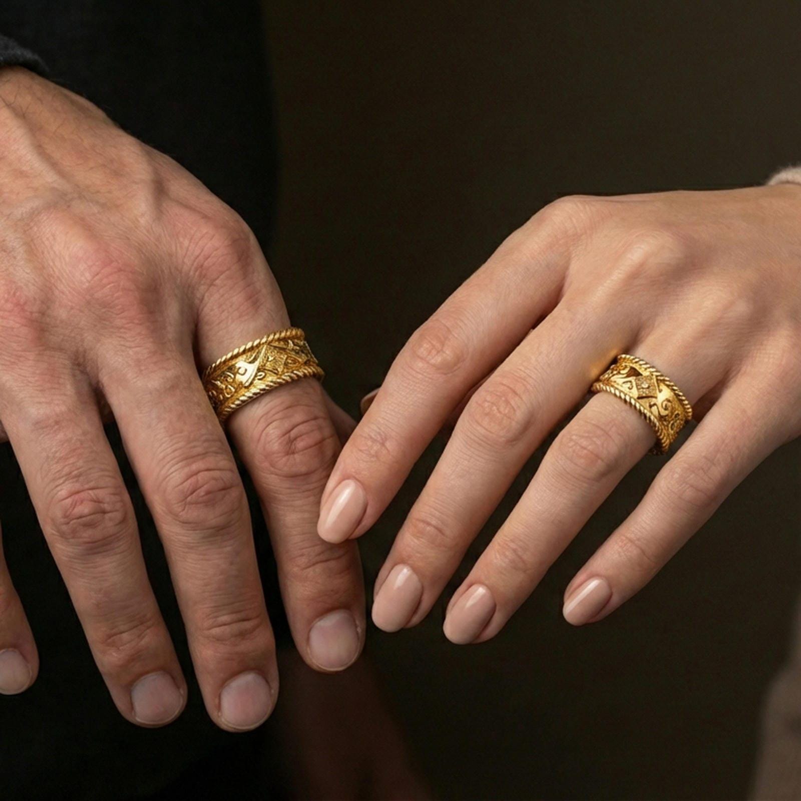 Gold plated rope edge engraved band worn on finger, ornate floral panel with scrollwork accents, premium lifestyle jewelry photo.