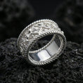 Load image into Gallery viewer, Polished silver rope border engraved band ring on black volcanic stone, crisp floral panel and vintage scrollwork detail, centered close-up studio lighting.
