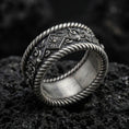 Load image into Gallery viewer, Oxidized sterling silver rope edge band ring on dark volcanic rock, ornate floral and scroll engraving, premium macro product shot.
