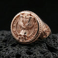 Load image into Gallery viewer, Rose gold plated owl signet ring with skull centerpiece and “THE WISE ARE SILENT” inscription, macro photo on black volcanic rock
