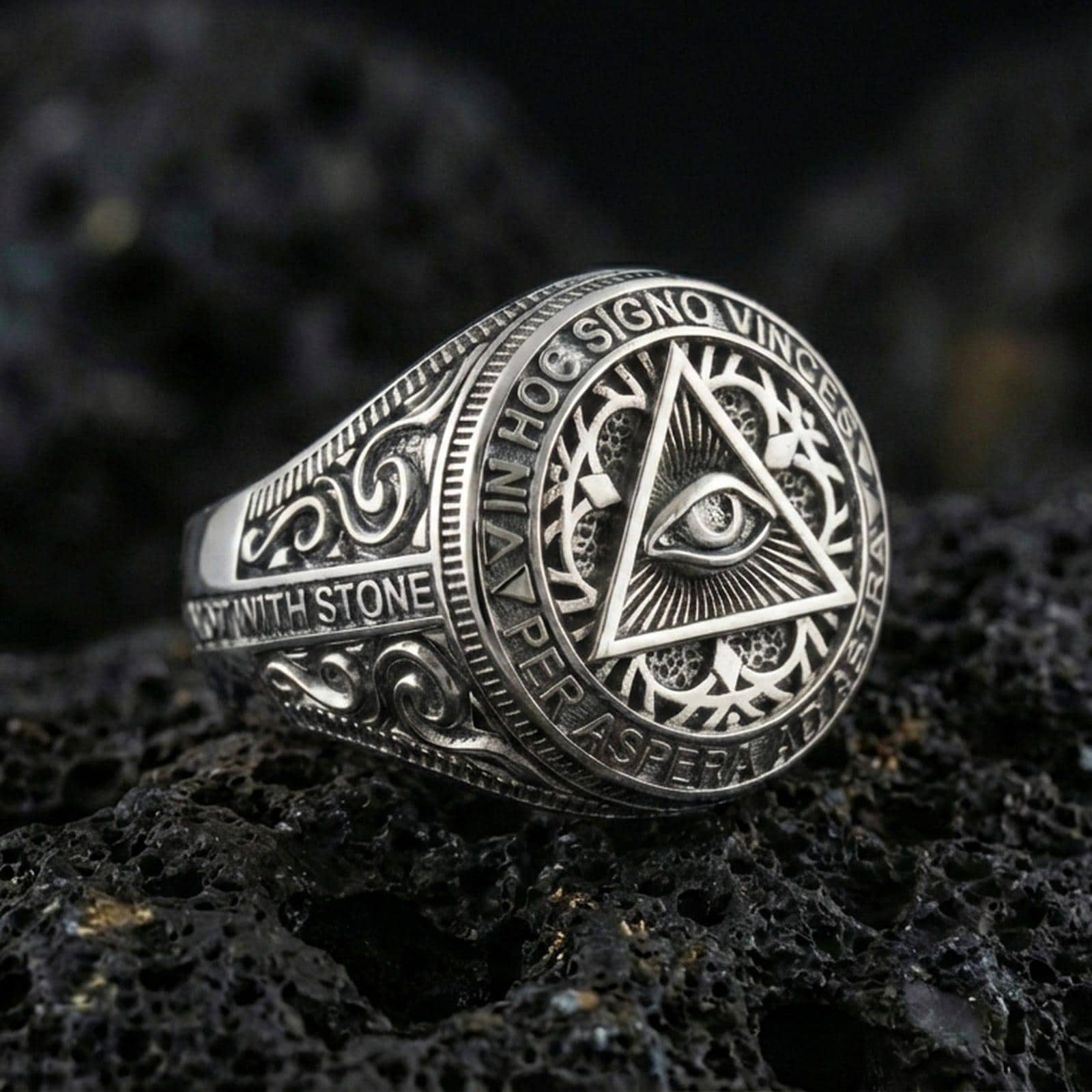 Polished silver Masonic eye-in-triangle signet ring with circular Latin motto border and ornate side engraving, on volcanic stone