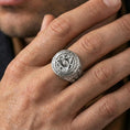 Load image into Gallery viewer, Polished silver Masonic eye-in-triangle ring on the finger, wearable macro focusing on the circular inscription and relief details
