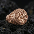 Load image into Gallery viewer, Rose gold plated Masonic eye triangle ring with engraved filigree sides and Latin inscription border, macro on black volcanic rock
