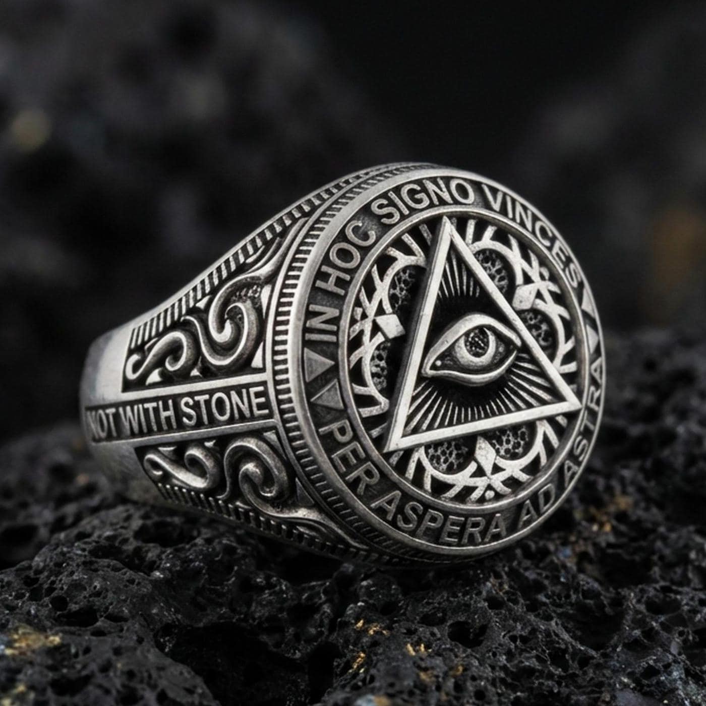 Oxidized sterling silver all-seeing eye triangle ring with Latin inscription and engraved scrollwork, macro on black volcanic rock