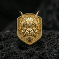 Load image into Gallery viewer, Gold plated oni mask signet ring featuring horned demon face carving and textured shield-shaped face, macro on volcanic rock
