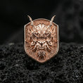 Load image into Gallery viewer, Rose gold plated Japanese oni mask ring with sculpted horns and fierce facial expression, close-up on black volcanic stone
