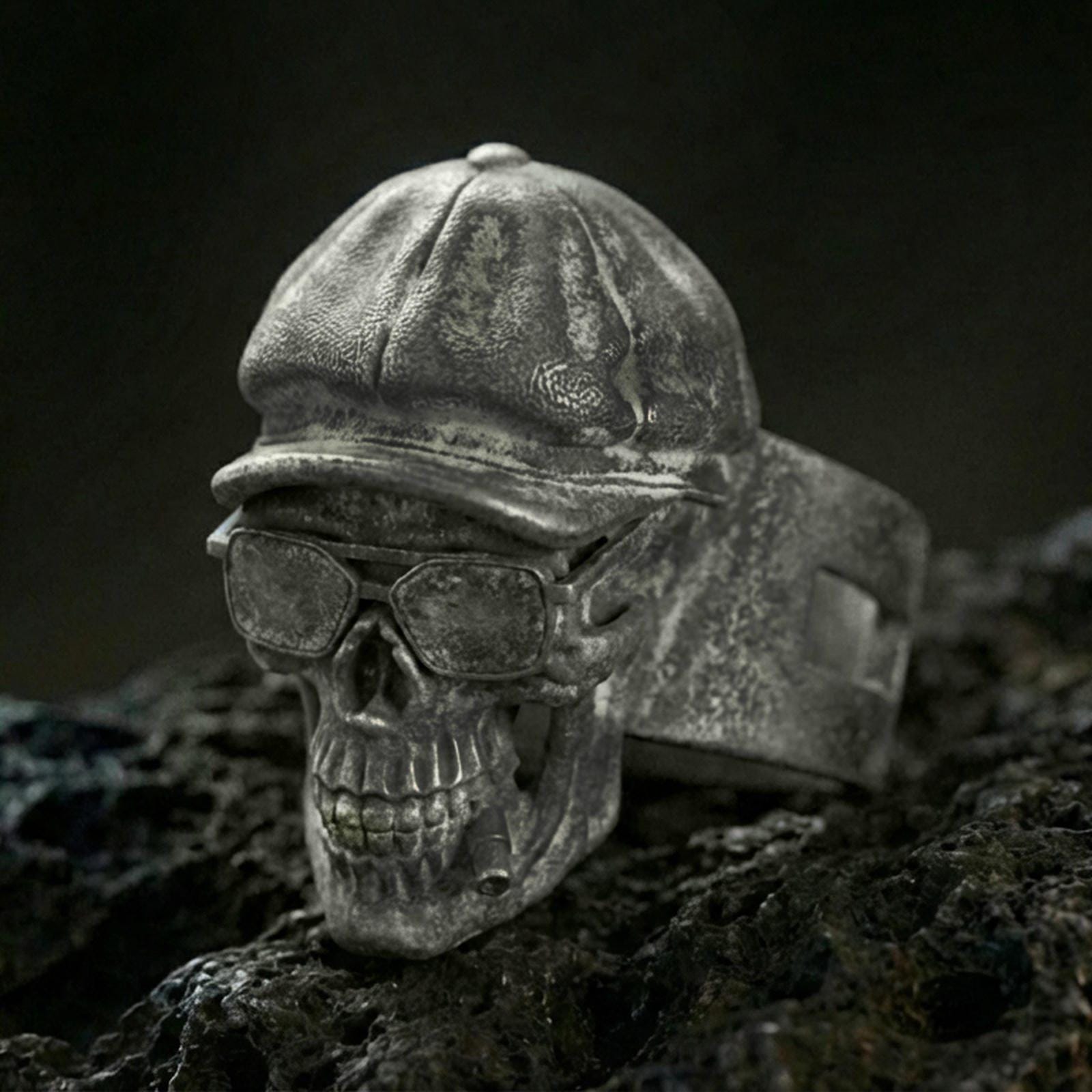 Sterling silver skull ring with an oxidized finish, wearing a vintage cap and glasses, macro on black volcanic rock