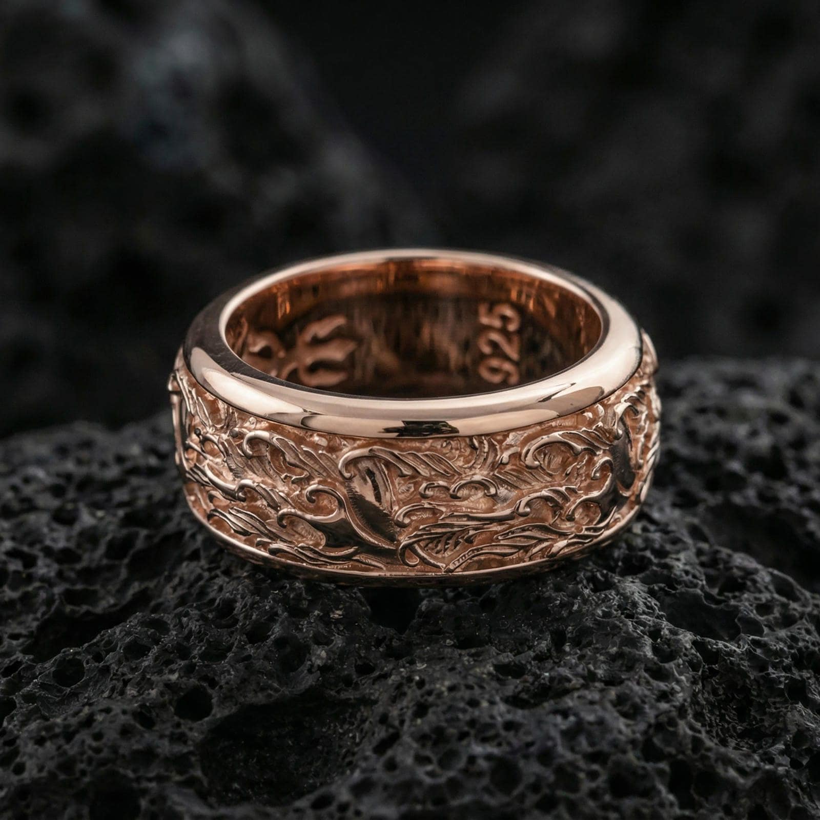 Rose gold plated sterling silver spinner wave band on volcanic stone, intricate ocean wave relief with deep contrast, minimal high-end close-up.