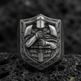 Load image into Gallery viewer, Sterling silver knight signet ring with an oxidized finish, shield-shaped face showing an armored warrior holding a sword, macro on black volcanic rock
