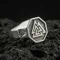 Load image into Gallery viewer, Sterling silver Valknut signet ring in a polished silver finish, octagonal signet face with a raised Norse knot emblem, close-up on volcanic stone
