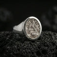 Load image into Gallery viewer, Sterling silver Valknut signet ring in a polished silver finish, circular signet face with the Valknut symbol and engraved root pattern, close-up on volcanic stone
