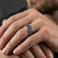 Load image into Gallery viewer, Oxidized sterling silver geometric spinner ring worn on finger, raised circle pattern detail on rotating center, natural lifestyle hand shot with shallow depth of field.

