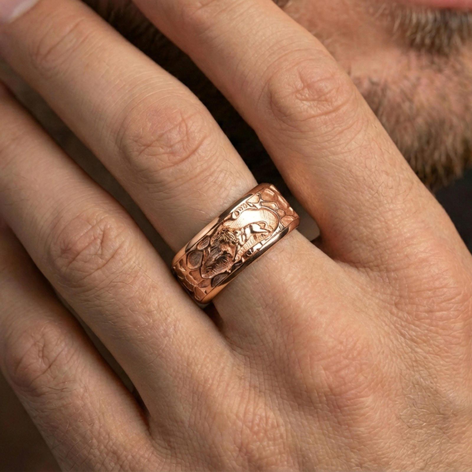 Rose gold plated lion spinner band ring worn on finger, sculpted lion scene relief with textured edges, elegant lifestyle wear shot.