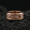 Load image into Gallery viewer, Rose gold plated sterling silver lion spinner band on volcanic stone, sculpted lion scene relief with deep contrast and textured edges, minimal high-end close-up.
