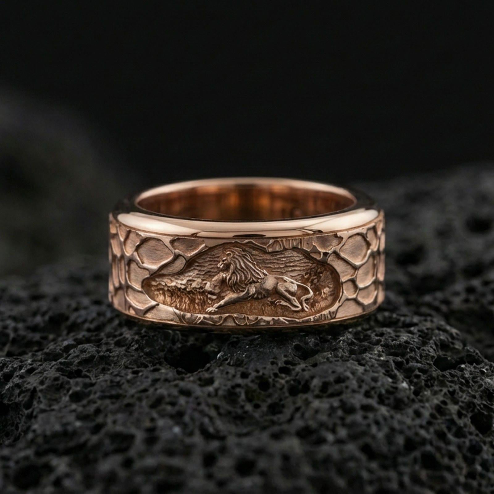 Rose gold plated sterling silver lion spinner band on volcanic stone, sculpted lion scene relief with deep contrast and textured edges, minimal high-end close-up.