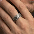 Load image into Gallery viewer, Oxidized sterling silver spinning lion band worn on finger, lion scene detail on rotating center, natural lifestyle hand shot with shallow depth of field.
